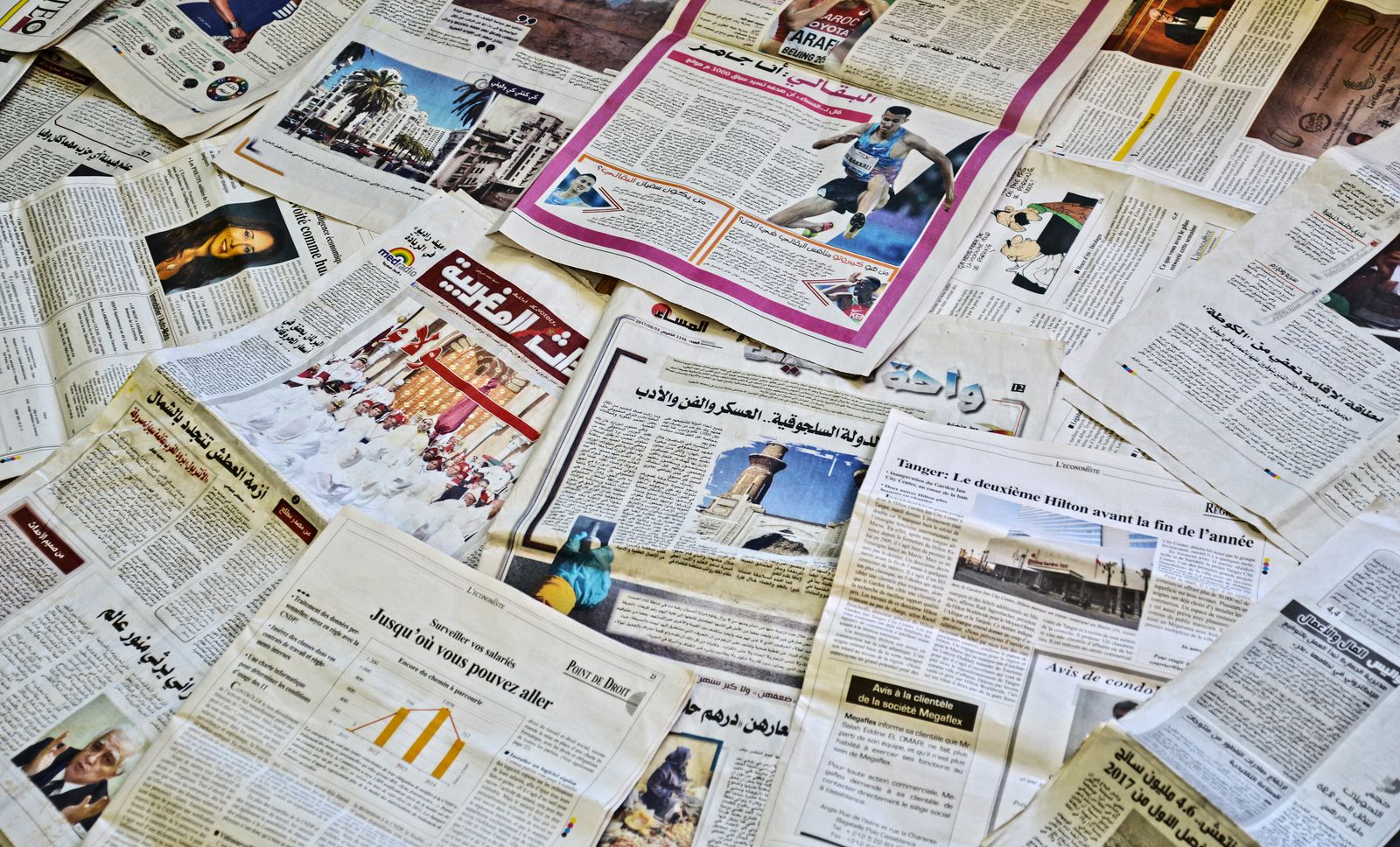 Vue rapprochée de divers journaux disposés, mettant en valeur des titres et des articles variés.
