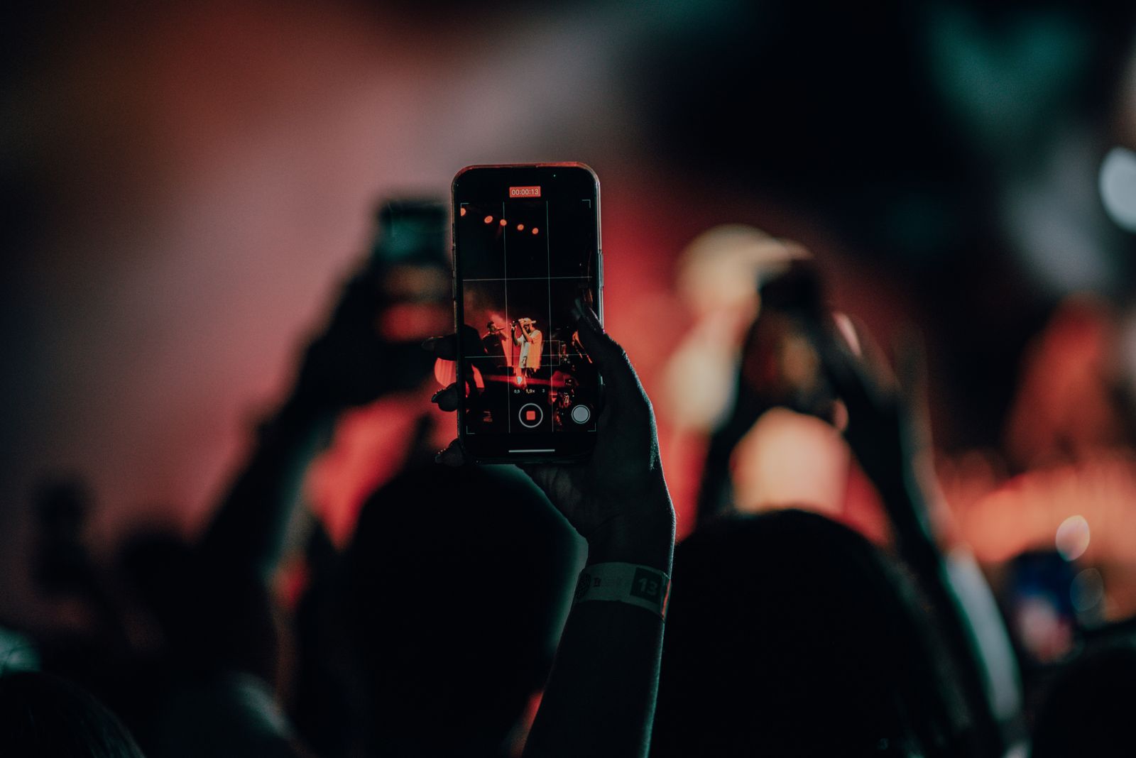 Un gros plan d'un smartphone enregistrant une scène de concert animée avec des lumières de scène colorées.